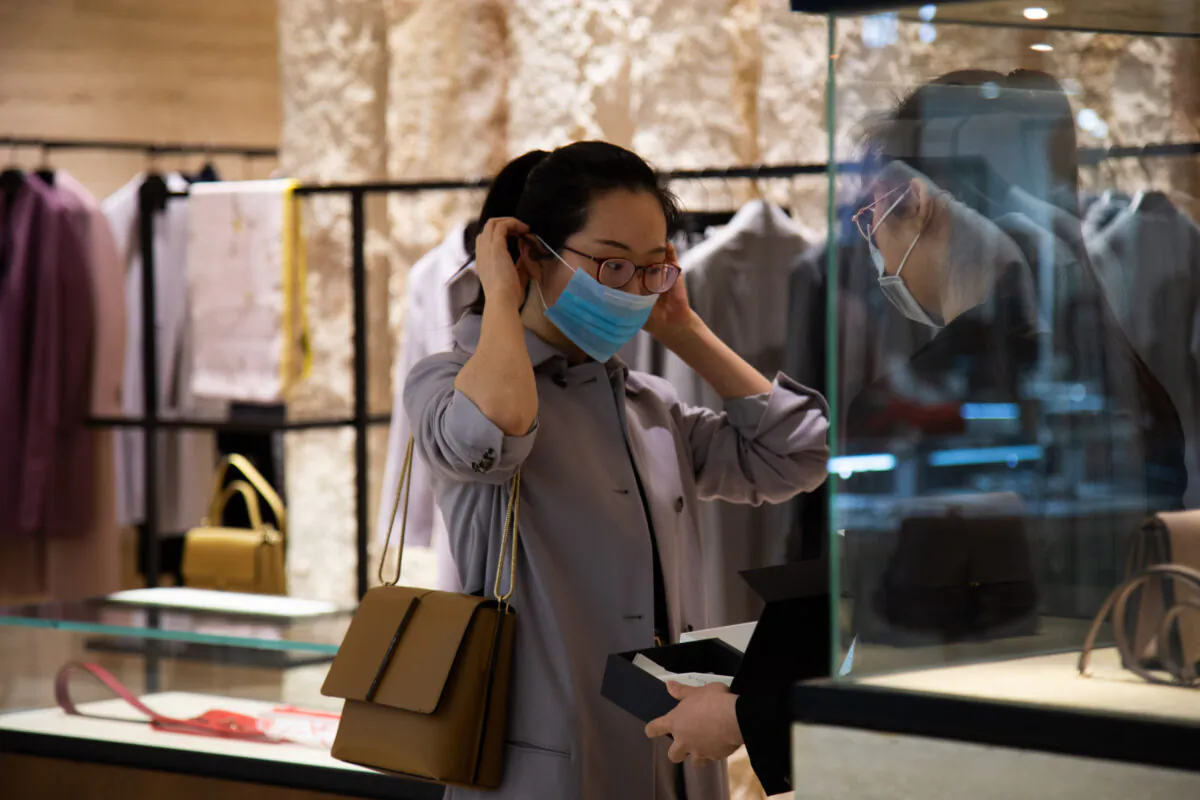 A woman puts on a mask in a shopping mall in Wangfujing in Beijing on Jan. 26, 2020. (Betsy Joles/Getty Images)