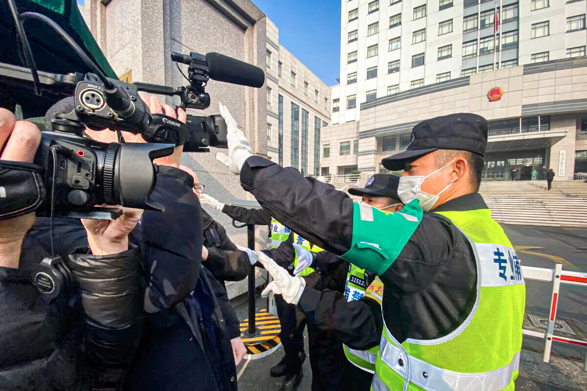 A policeman covers a camera to stop journalists from recording footage outside the Shanghai Pudong New District People's Court, where Chinese citizen journalist Zhang Zhan is set for trial in Shanghai on Dec. 28, 2020. (Leo Ramirez/AFP via Getty Images)