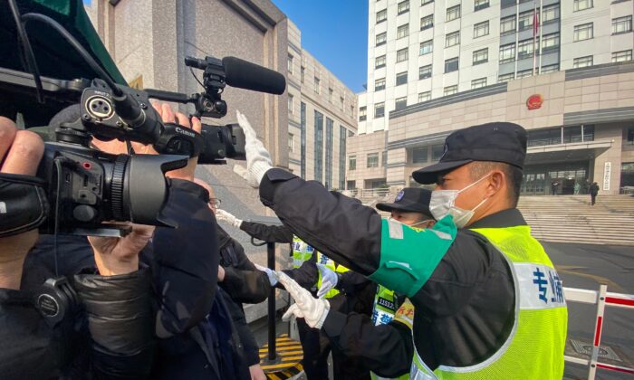 A policeman covers a camera to stop journalists from recording footage outside the Shanghai Pudong New District People's Court, where Chinese citizen journalist Zhang Zhan is set for trial in Shanghai, China, on Dec. 28, 2020. (Leo Ramirez/AFP via Getty Images)