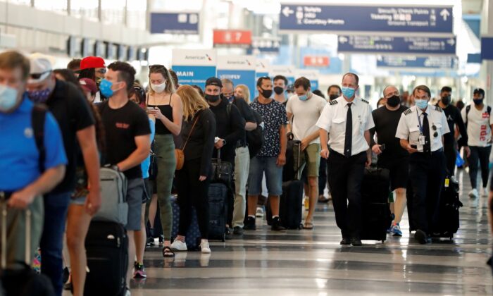 Two airplane pilots pass by a line of passengers while waiting at a security check-in line at O'Hare International Airport in Chicago, Ill., on July 1, 2021. (Shafkat Anowar/AP Photo)