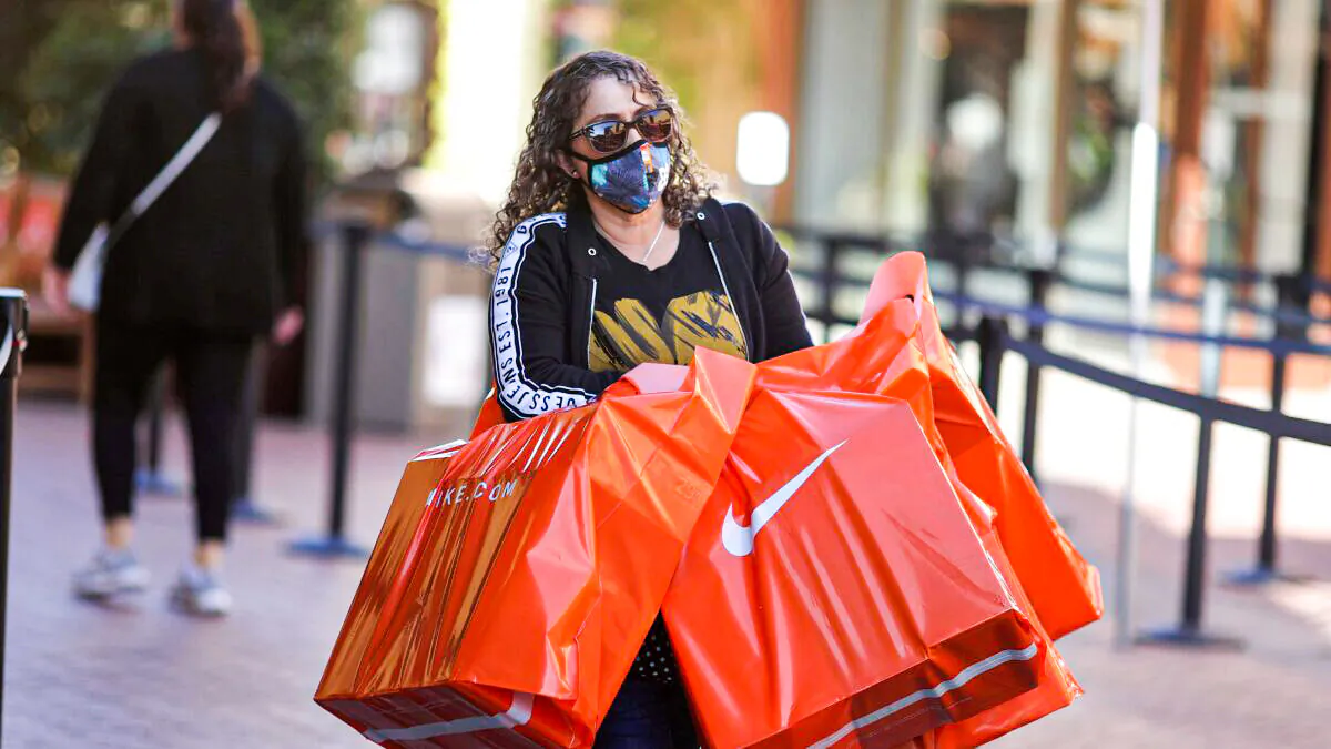 A woman carries Nike shopping bags at the Citadel Outlet mall in Commerce, Calif., on Dec. 3, 2020. (Lucy Nicholson/Reuters)