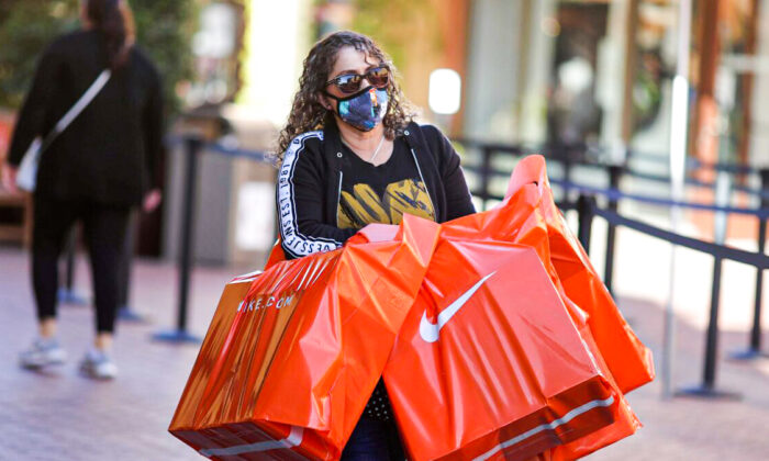 A woman carries Nike shopping bags at the Citadel Outlet mall in Commerce, Calif., on Dec. 3, 2020. (Lucy Nicholson/Reuters)