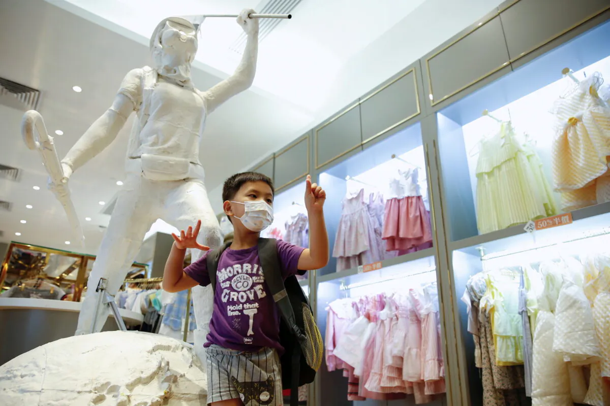 A child poses next to the two-meter-tall "Lady Liberty," a symbolic statue placed by pro-democracy protesters at a Chickeeduck branch in Hong Kong on June 18, 2020. (Tyrone Siu/Reuters)