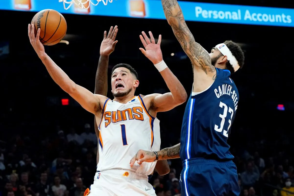Phoenix Suns guard Devin Booker (1) shoots past Dallas Mavericks center Willie Cauley-Stein (33) during the second half of an NBA basketball game in Phoenix, on Nov. 17, 2021. (Matt York/AP Photo)