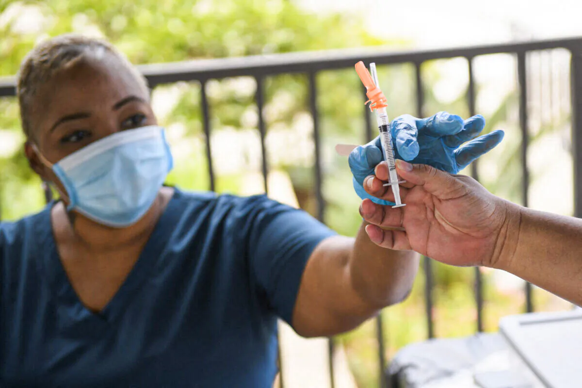 A nurse is handed a dose of the Pfizer COVID-19 vaccine before administering it to a college student at a mobile vaccination clinic at the California State University Long Beach campus in Calif., on Aug. 11, 2021. (Patrick T. Fallon/AFP via Getty Images)