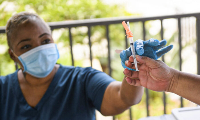 A nurse is handed a dose of the Pfizer COVID-19 vaccine before administering it to a college student at a mobile vaccination clinic at the California State University Long Beach campus in Calif., on Aug. 11, 2021. (Patrick T. Fallon/AFP via Getty Images)