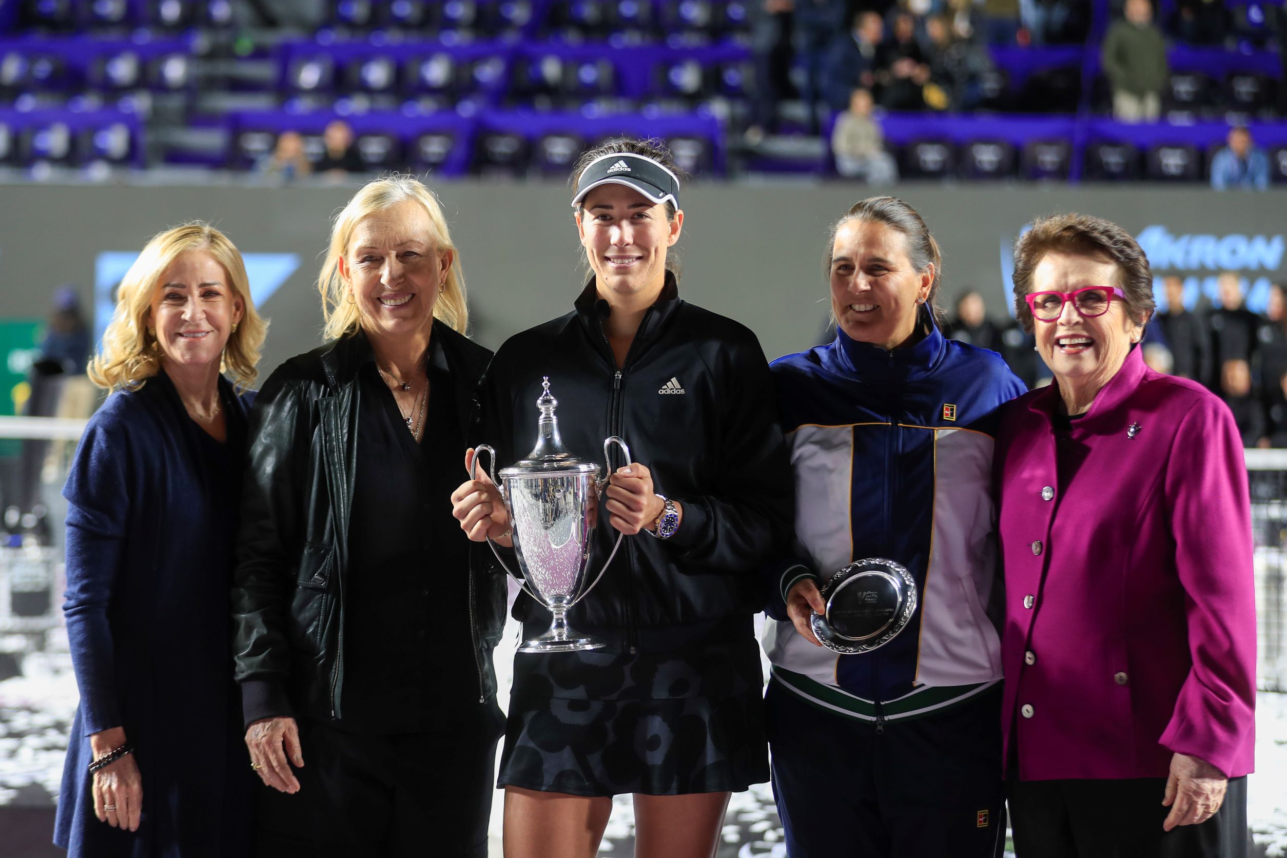 Garbiñe Muguruza, of Spain, (C), holds the trophy