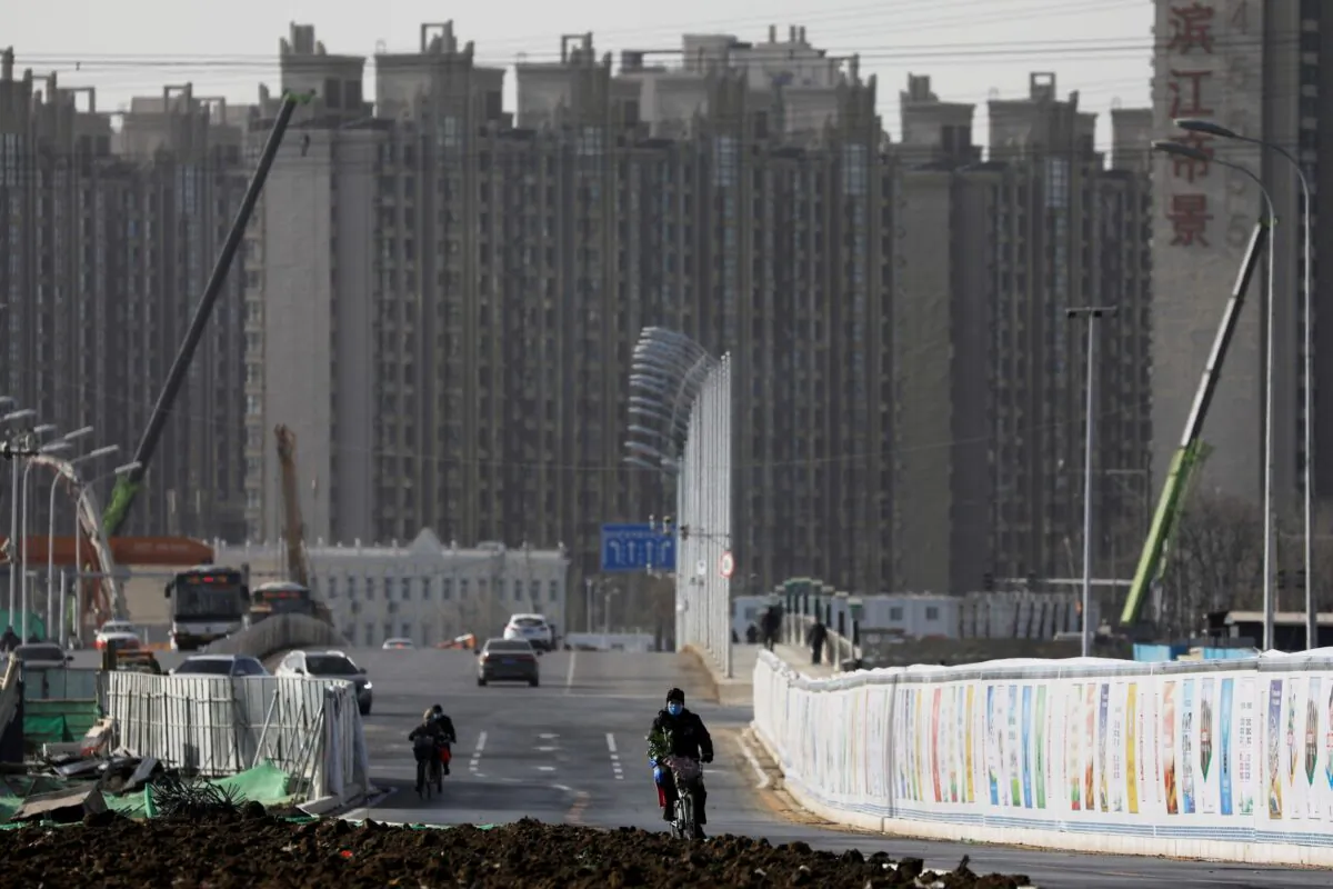 A man rides a bicycle next to a construction site near residential buildings in Beijing, China on Jan. 13, 2021. (Tingshu Wang/Reuters)