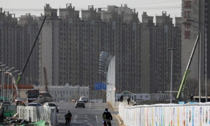 A man rides a bicycle next to a construction site near residential buildings in Beijing, China on Jan. 13, 2021. (Tingshu Wang/Reuters)
