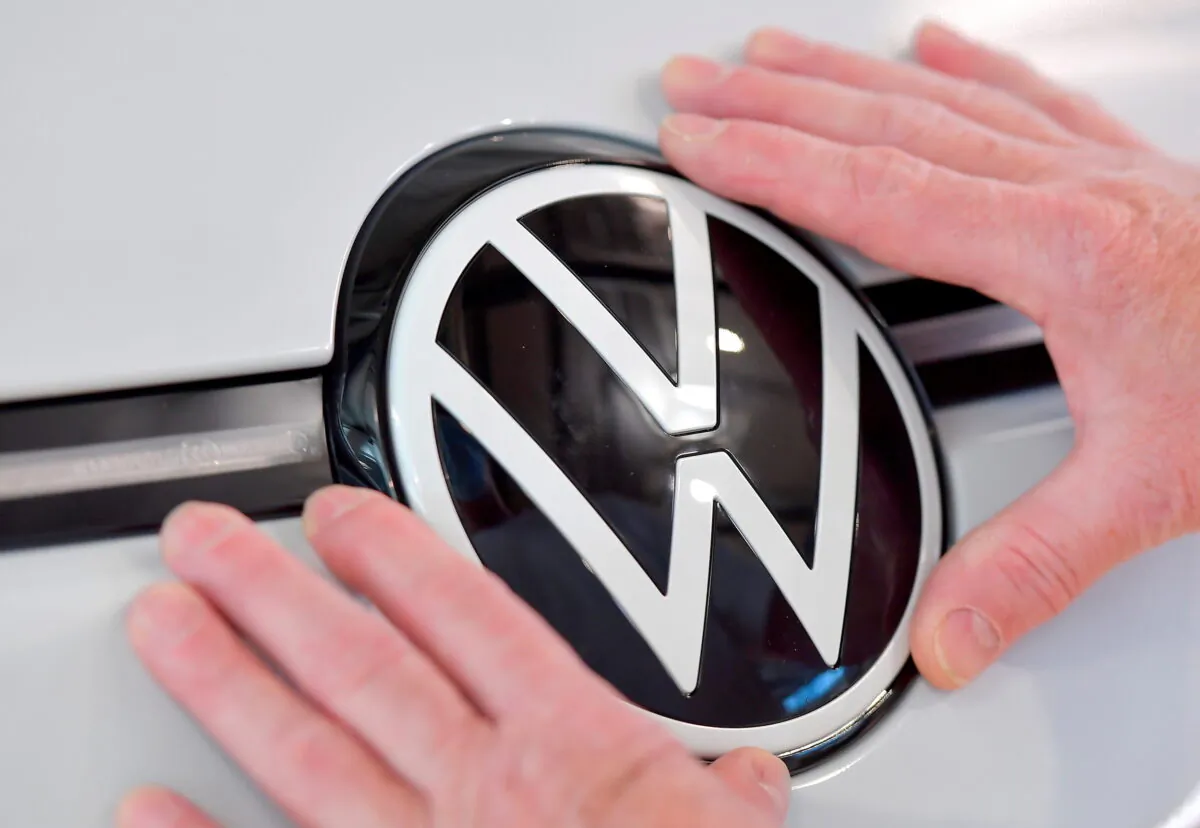 A technician fixes a VW sign in the assembly line of German carmaker Volkswagen's electric ID. 3 car in Dresden, Germany, on June 8, 2021. (Matthias Rietschel/Reuters)