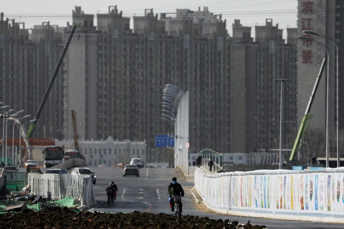 A man rides a bicycle next to a construction site near residential buildings in Beijing, on Jan. 13, 2021. (Tingshu Wang/Reuters)