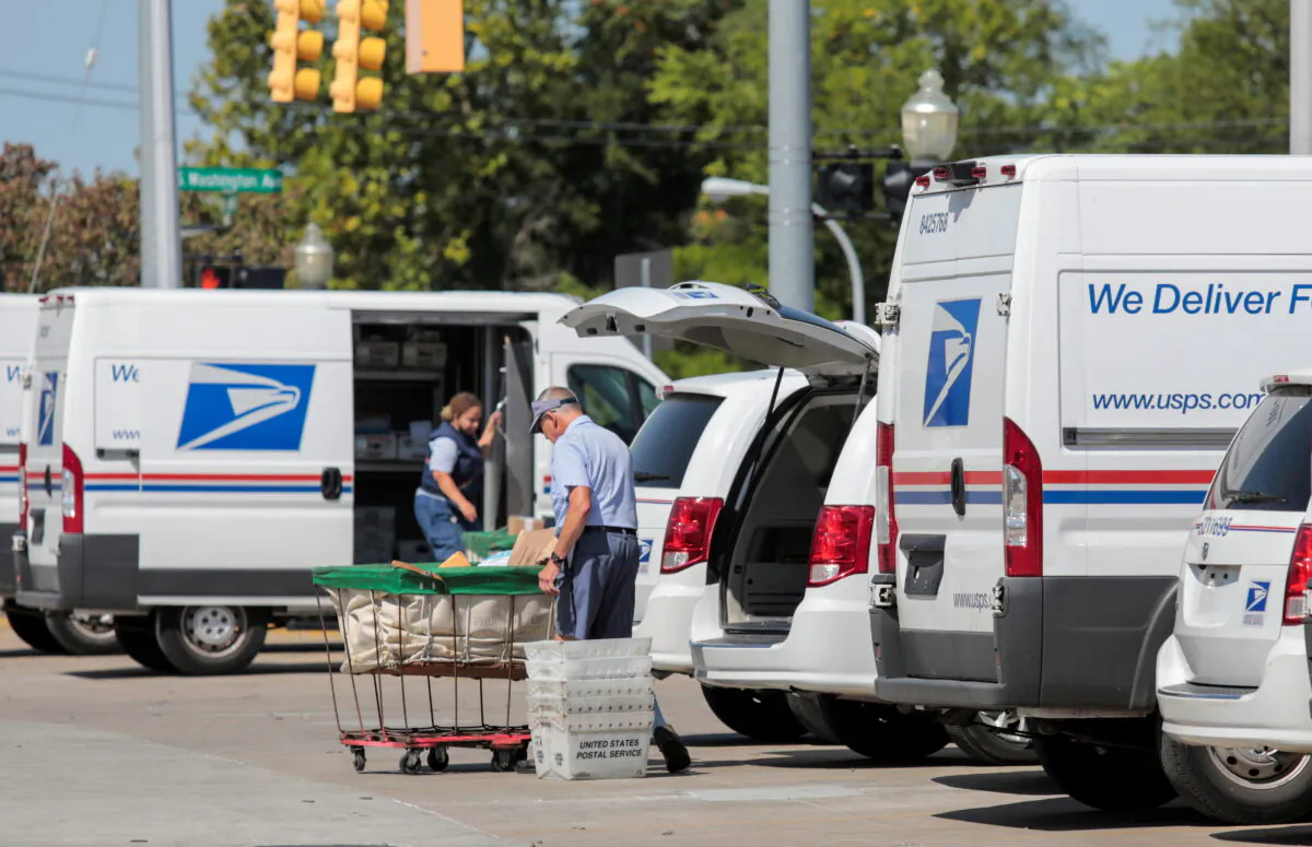 U.S. Postal Service (USPS) workers load mail into delivery trucks outside a post office in Royal Oak, Mich., on Aug. 22, 2020. (Rebecca Cook/Reuters)