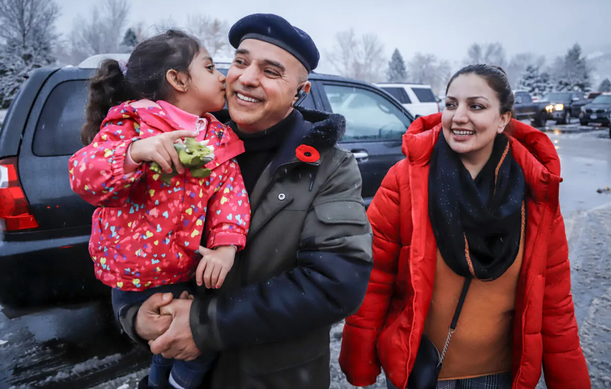 Evacuated residents from Merritt, B.C., Barkad Khan, (C), holds his daughter Mahira Khan, 4, as his wife Afreen Khan, looks on while they gather at a reception centre in Kamloops, B.C., on Nov. 18, 2021. (The Canadian Press/Jeff McIntosh)