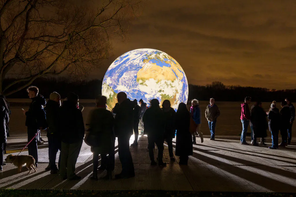 People view artist Luke Jerram's new 'Floating Earth' Debuts In Wigan, England, on Nov. 18, 2021. (Christopher Furlong/Getty Images)