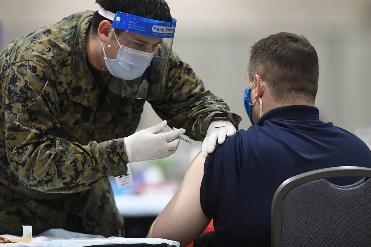 A member of the U.S. Armed Forces administers a COVID-19 vaccine to a police officer at a FEMA community vaccination center in Philadelphia, Pa., on March 2, 2021. (Mark Makela/Getty Images)
