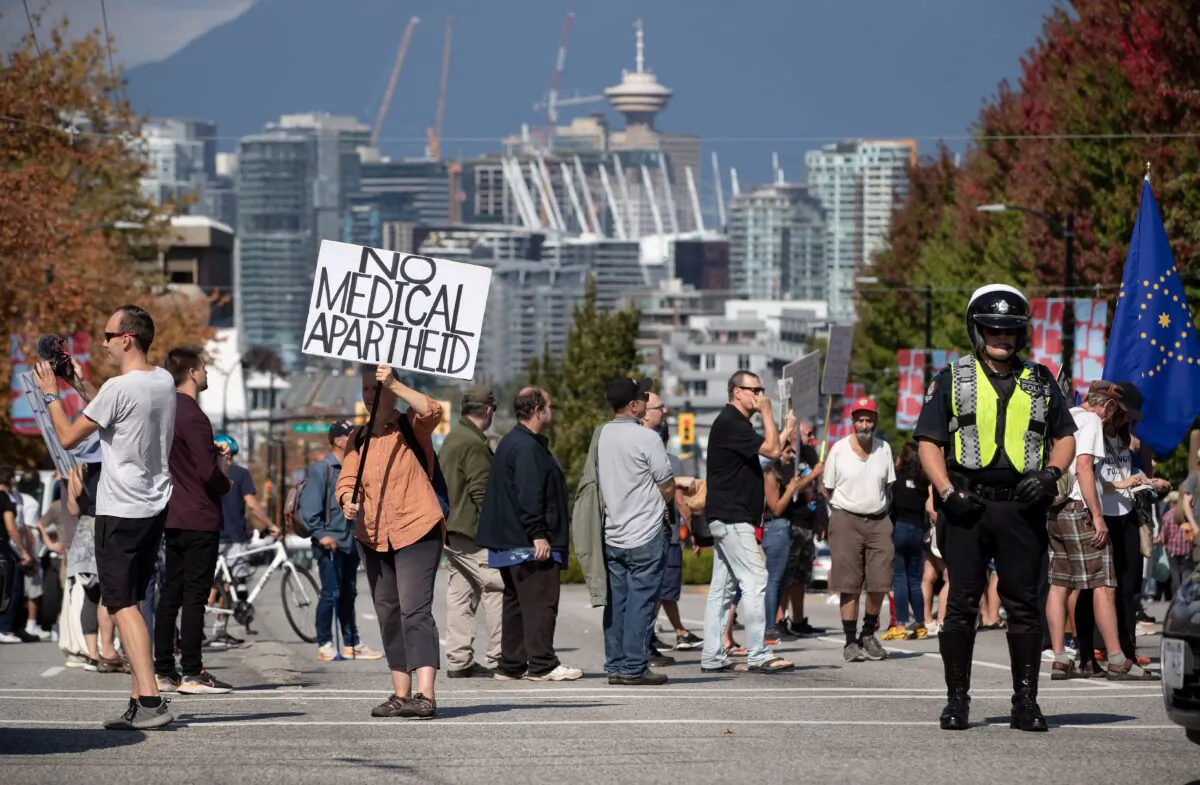 A police officer stands by as people attend a rally and march against COVID-19 vaccination mandates and public health measures, in Vancouver on Sept. 8, 2021. (The Canadian Press/Darryl Dyck)