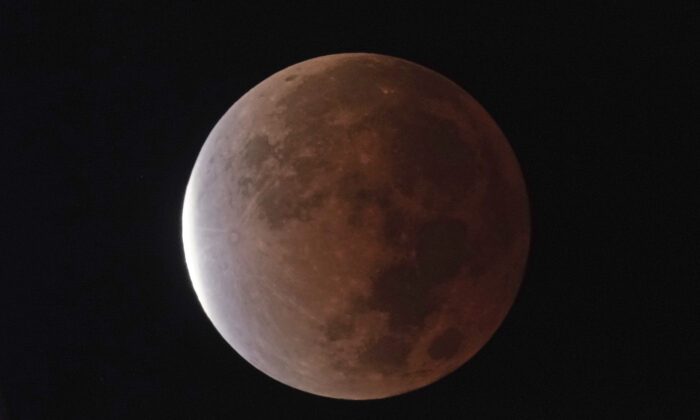 The earth's shadow covers the full moon during a partial lunar eclipse in Kansas City, Mo, Nov. 19, 2021. (Charlie Riedel/AP Photo)