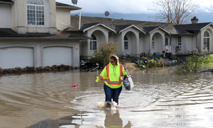A resident of the Yarrow neighbourhood wades through floodwaters outside her home after rainstorms caused flooding and landslides in Chilliwack, British Columbia, Canada, on Nov. 20, 2021. (Jesse Winter/Reuters)