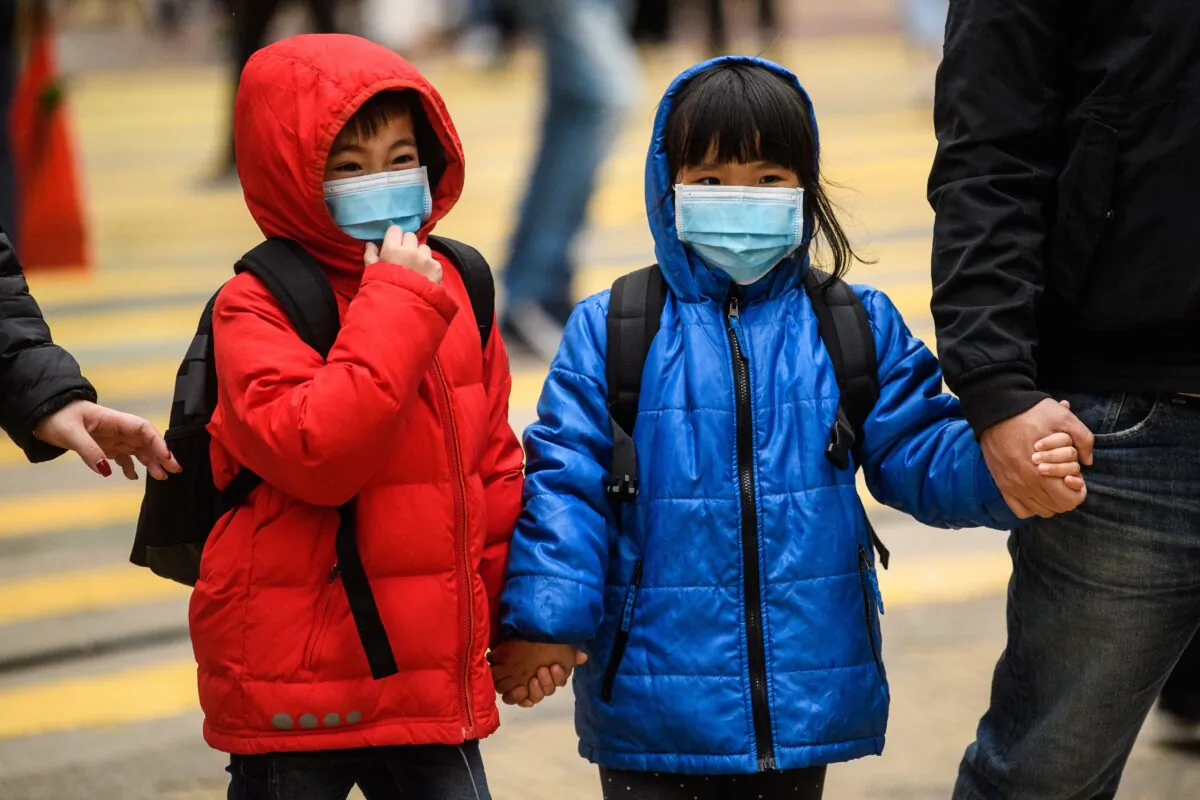 Children wearing masks cross a road during a Lunar New Year of the Rat public holiday in Hong Kong on Jan. 27, 2020. (Anthony Wallace/AFP via Getty Images)