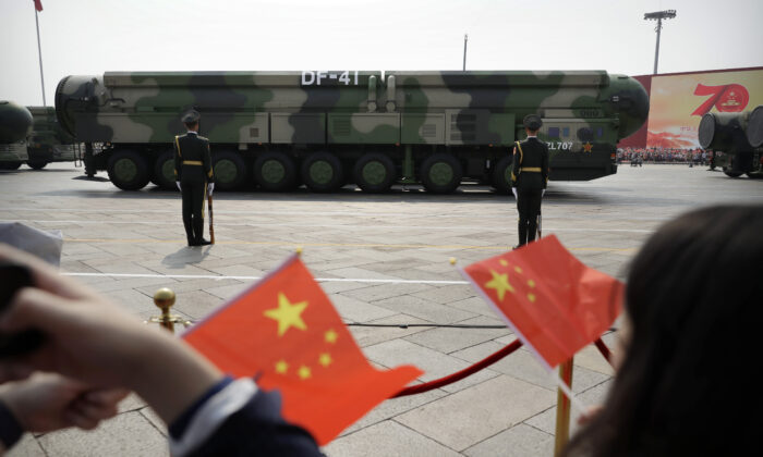 Spectators wave Chinese flags as military vehicles carrying DF-41 ballistic missiles roll during a parade to commemorate the 70th anniversary of the founding of Communist China in Beijing, Oct. 1, 2019. (AP Photo/Mark Schiefelbein)