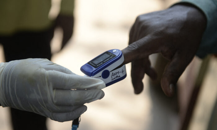 A health worker uses an oximeter to monitor the oxygen saturation levels of a resident during a door-to-door survey to check for COVID-19 symptoms at a low income neighbourhood in Hyderabad, India, on May 6, 2021. (Noah Seelam/AFP via Getty Images)