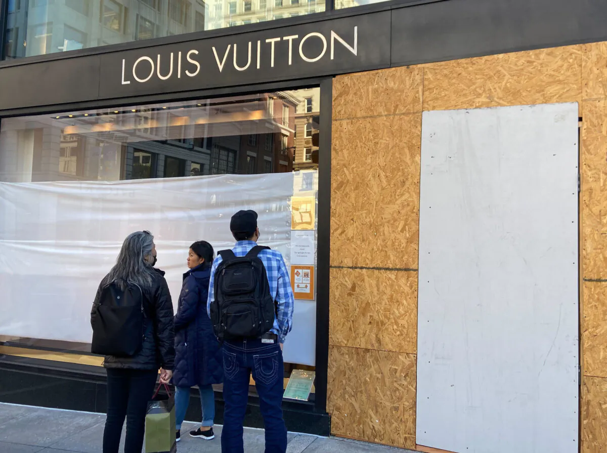 Union Square visitors look at damage to the Louis Vuitton store in San Francisco on Nov. 21, 2021, after looters ransacked businesses late into the night of Nov. 21. (Danielle Echeverria/San Francisco Chronicle via AP)