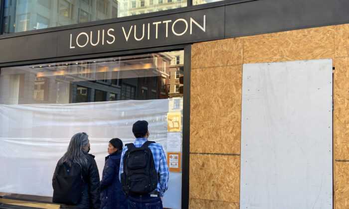 Union Square visitors look at damage to the Louis Vuitton store in San Francisco on Nov. 21, 2021, after looters ransacked businesses late into the night of Nov. 21. (Danielle Echeverria/San Francisco Chronicle via AP)