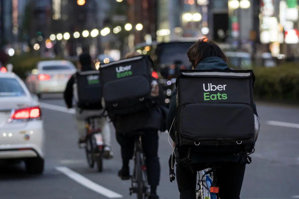 Uber Eats delivery men ride bicycles through the Kabukicho entertainment area in Tokyo, Japan, on April 11, 2020. (Tomohiro Ohsumi/Getty Images)