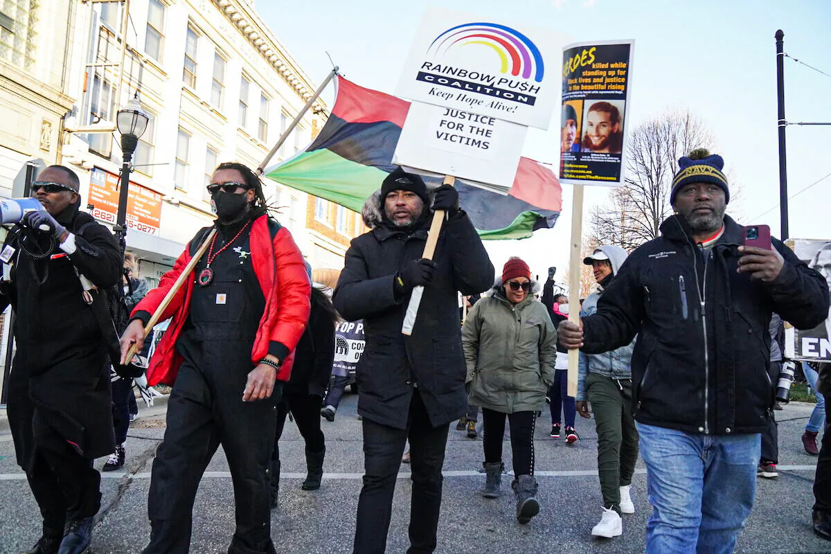 Justin Blake, Jacob Blake's uncle, waves a UNIA flag as he leads a march protesting Kyle Rittenhouse's acquittal by jury in Kenosha, Wis., on Nov. 21, 2021. (Jackson Elliott/The Epoch Times)