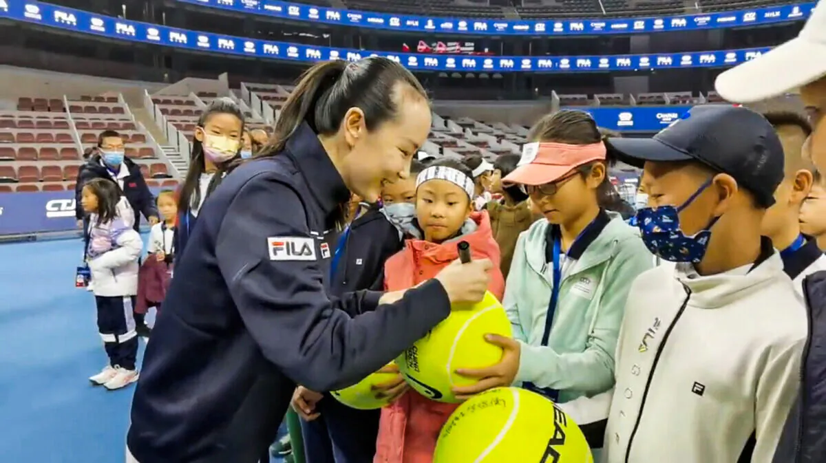 Chinese tennis player Peng Shuai signs large-sized tennis balls at the opening ceremony of Fila Kids Junior Tennis Challenger Final in Beijing on Nov. 21, 2021, in this screen grab obtained from a social media video. (Twitter @qingqingparis via Reuters)