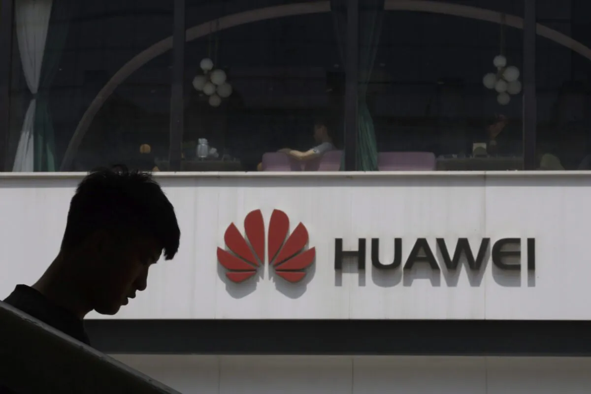 A Chinese man is silhouetted near the Huawei logo in Beijing on May 16, 2019. Conservative critics call for the federal government to ban the Chinese company from Canada's 5G network due to security concerns. (AP Photo/Ng Han Guan)