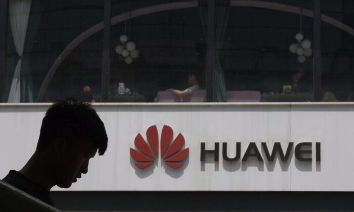 A Chinese man is silhouetted near the Huawei logo in Beijing on May 16, 2019. Conservative critics call for the federal government to ban the Chinese company from Canada's 5G network due to security concerns. (AP Photo/Ng Han Guan)