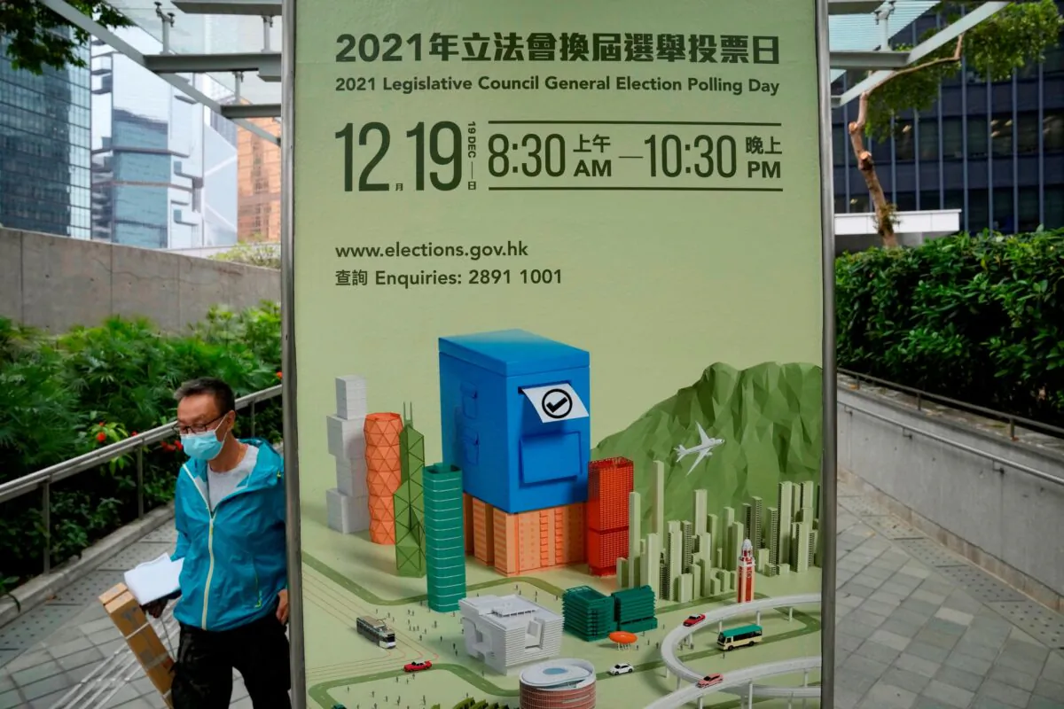 A man walks past a banner promoting the upcoming legislative elections in Hong Kong, on Nov. 23, 2021. (Kin Cheung/AP Photo)