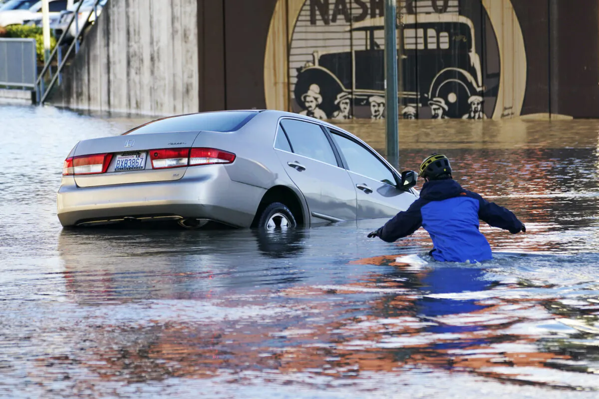A man races into the water to help rescue the driver of a car that went into the flooded Nooksack River in Ferndale, Wash. on Nov. 16, 2021. (Elaine Thompson/AP Photo)
