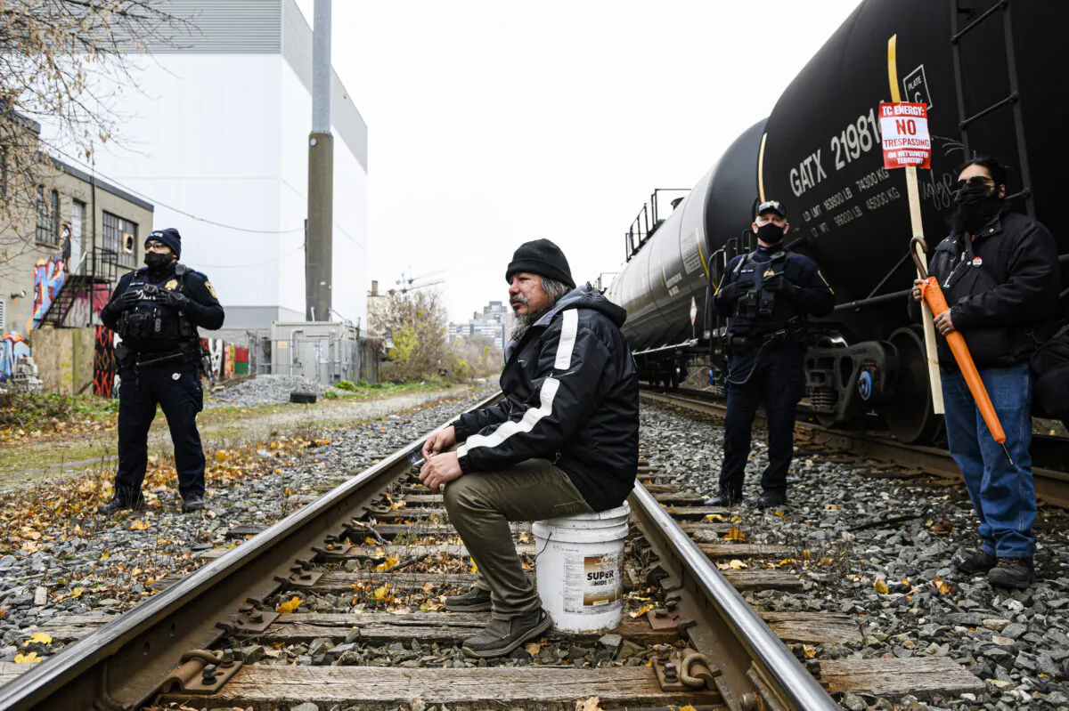 A man blocks a rail line in support of Wet'suwet'en protesters who were arrested by the RCMP in northern B.C., in Toronto on Nov. 21, 2021. (The Canadian Press/Christopher Katsarov)