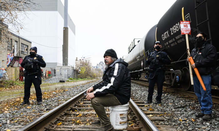 A man blocks a rail line in support of Wet'suwet'en protesters who were arrested by the RCMP in northern B.C., in Toronto on Nov. 21, 2021. (The Canadian Press/Christopher Katsarov)