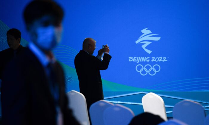A man takes pictures of a logo of the Beijing 2022 Winter Olympic Games during the Beijing 2022 Paralympic Winter Games 100 Day countdown event at the National Aquatic Centre in Beijing, on Nov. 24, 2021. (Wang Zhao/AFP via Getty Images)