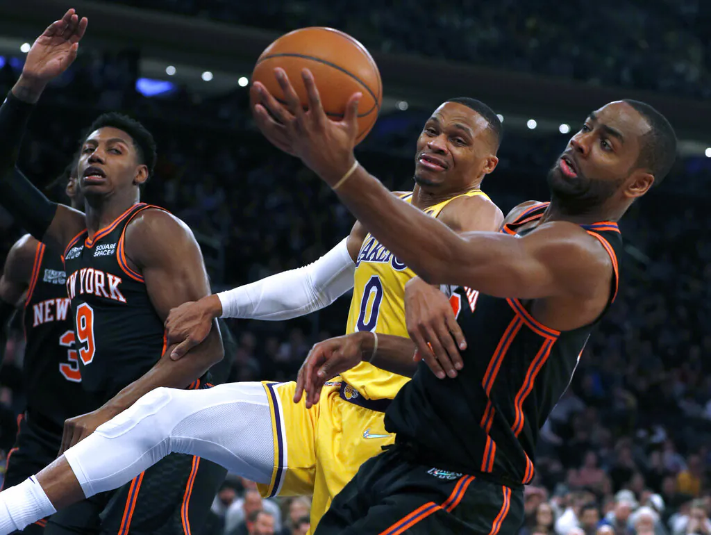 Los Angeles Lakers guard Russell Westbrook (0) and New York Knicks guard Alec Burks (18) vie for a rebound as Knicks' RJ Barrett (9) watches during the first half of an NBA basketball game in New York, on Nov. 23, 2021. (Jim McIsaac/AP Photo)