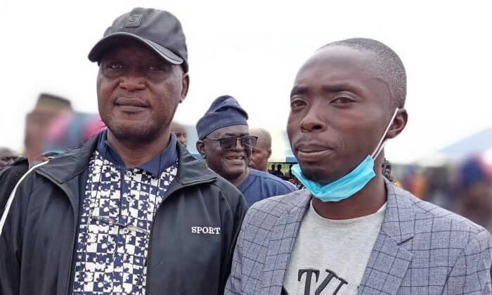 Luka Binniyat, left and Lawrence Zongo, right, contributors to   Pezou, standing at a mass burial for victims of the Madamai village massacre, near Madamai, Nigeria on Sept. 30, 2021. (Bitrus Adamu) 