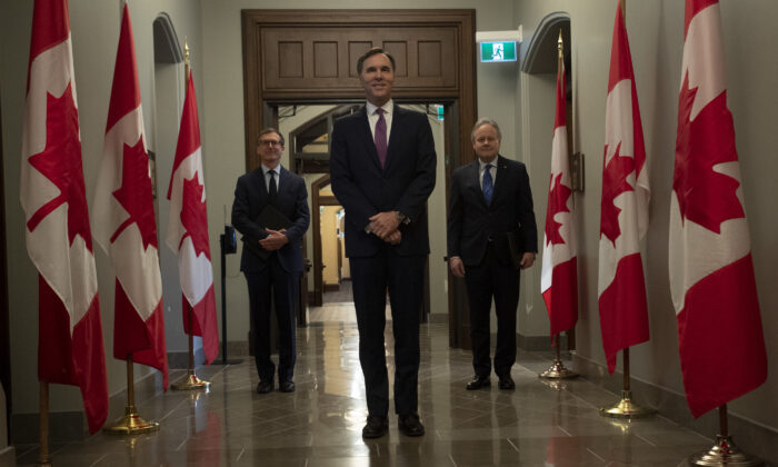 Finance Minister Bill Morneau, Bank of Canada Governor Stephen Poloz (R), and Bank of Canada governor-designate Tiff Macklem (L) wait to enter the room for a news conference in Ottawa on May 1, 2020. In the context of financial repression, the central bank’s independence from the treasury or finance ministry is questioned. ( Canadian Press/Adrian Wyld) 