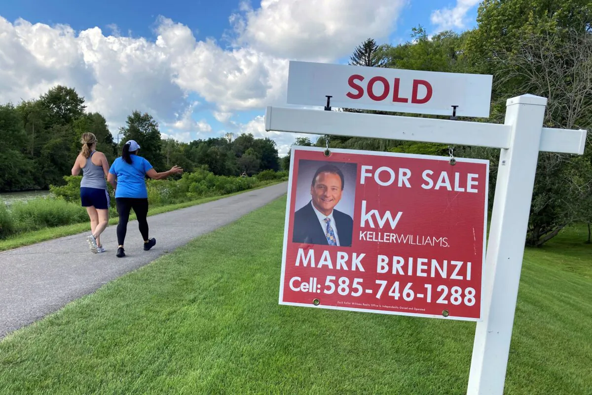 People walk by a sold sign in front of a house along the Erie Canal in Pittsford, N.Y., York, on Sept. 6, 2021. (Ted Shaffrey/AP Photo)