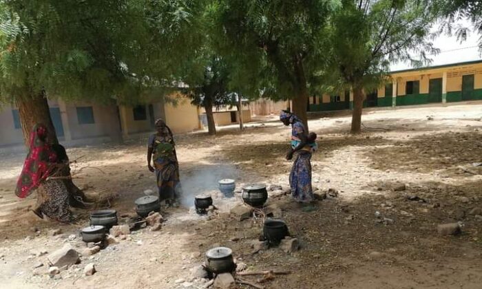 Displaced women cook in open space at an abandoned school in Gatawa town in Nigeria. (Mansur Isa Buhari)