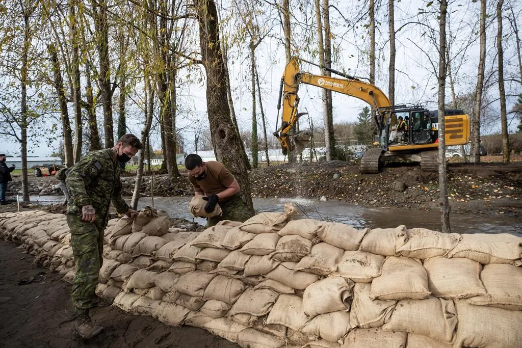 Members of the Canadian Forces build a temporary dike with sandbags behind houses on Clayburn Creek ahead of a rainfall warning Environment Canada has forecast for the region, in Abbotsford, B.C., on Nov. 24, 2021. (Darryl Dyck/The Canadian Press)