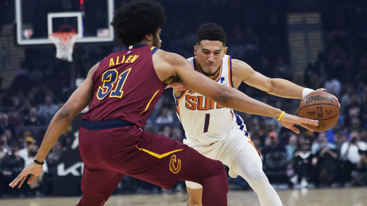 Phoenix Suns' Devin Booker (1) drives past Cleveland Cavaliers' Jarrett Allen (31) in the first half of an NBA basketball game in Cleveland, on Nov. 24, 2021. (Tony Dejak/AP Photo)