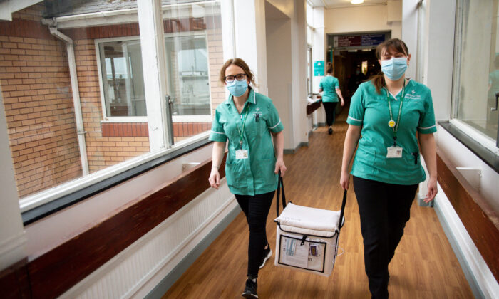Pharmacists transport a cooler containing the Moderna COVID-19 vaccine at the West Wales General Hospital in Carmarthen, Wales, on April 7, 2021. (Jacob King/Pool/AFP via Getty Images)