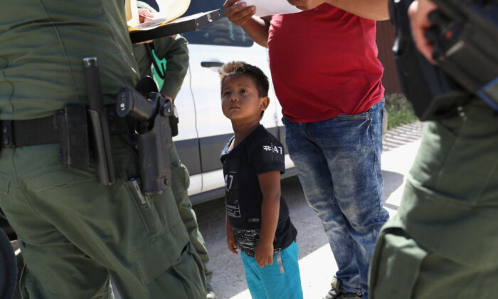  A boy and father from Honduras are taken into custody by U.S. Border Patrol agents near the U.S.-Mexico Border near Mission, Texas, on June 12, 2018. (John Moore/Getty Images)