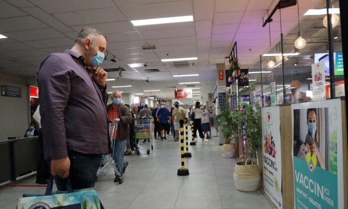 A shopper, wearing a face mask, looks at a poster for a COVID-19 vaccination center installed inside a supermarket in Brussels, on Aug. 30, 2021. (Bart Biesemans/Reuters)