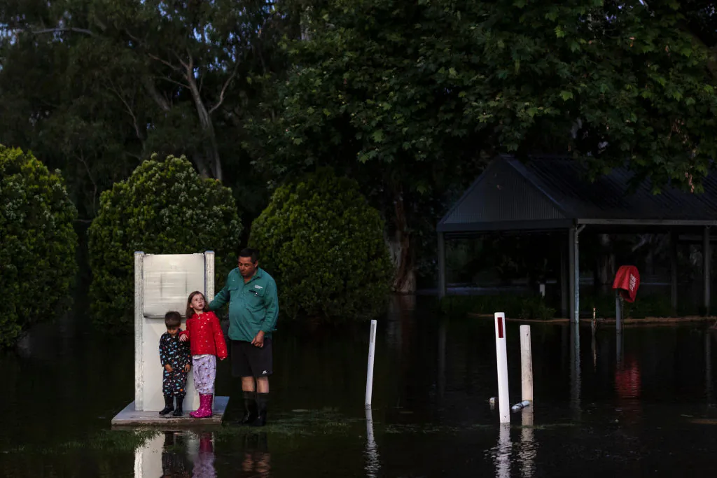 A family is seen on the banks of the Lachlan River as it begins to spill ahead of expected major flooding later tonight on November 16, 2021 in Forbes, Australia.(Photo by Brook Mitchell/Getty Images)