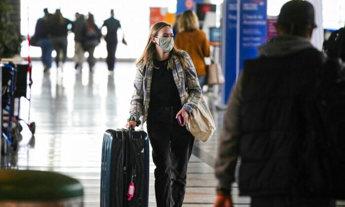 A traveler wears a face covering while heading to the American Airlines check-in counter as the Thanksgiving Day holiday approaches, on Nov. 23, 2021, at Denver International Airport. (AP Photo/David Zalubowski)