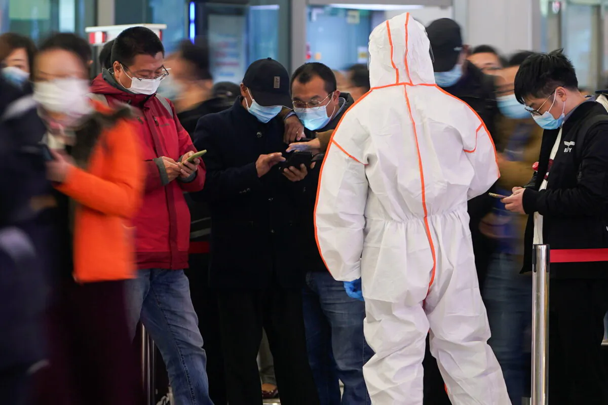 A security guard blocks an exit as he directs people to scan a QR code to track their health status at Shanghai Hongqiao Railway Station, following new cases of the coronavirus disease (COVID-19), in Shanghai, China, on Nov. 25, 2021. (Aly Song/Reuters)